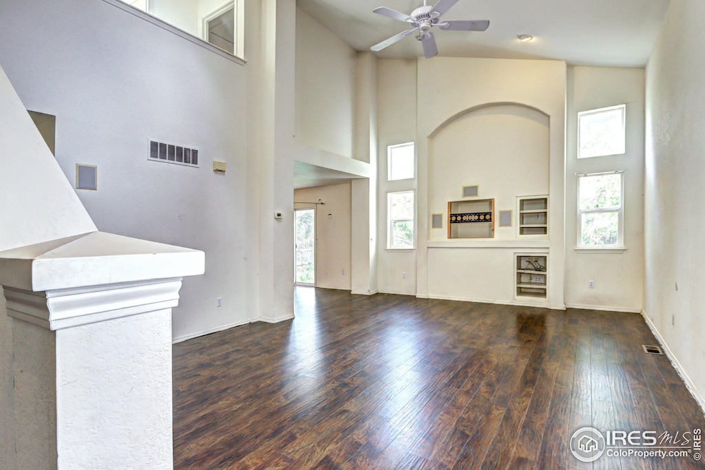 foyer with a wealth of natural light, a high ceiling, ceiling fan, and visible vents