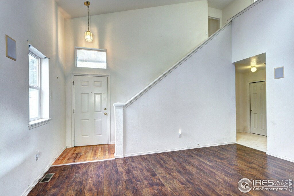 entryway featuring visible vents, baseboards, a towering ceiling, and wood finished floors