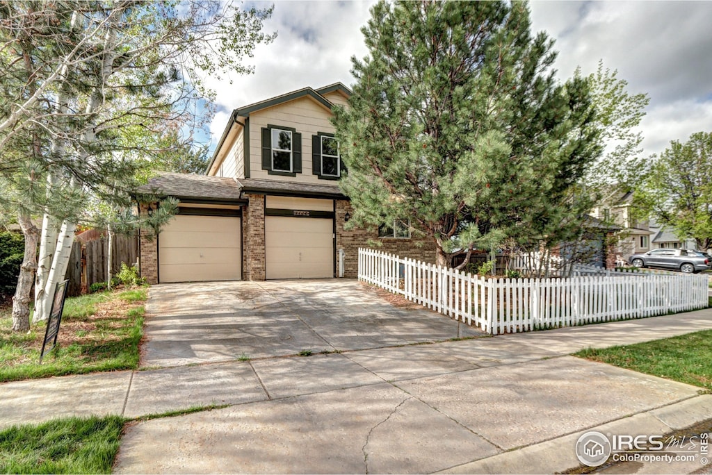 view of front facade with brick siding, a garage, fence private yard, and concrete driveway