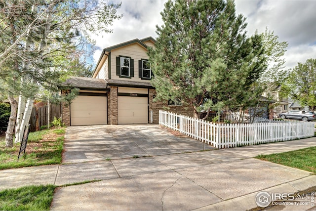 view of front facade with brick siding, a garage, fence private yard, and concrete driveway