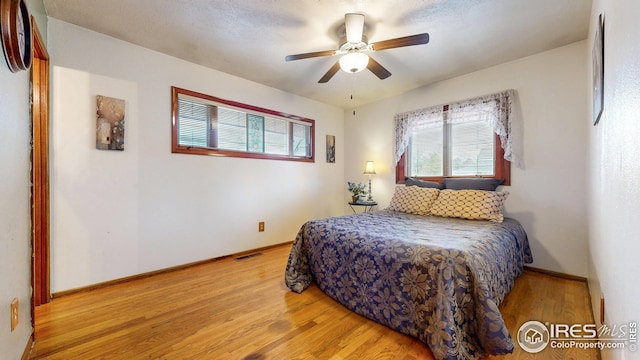 bedroom featuring baseboards, visible vents, ceiling fan, and light wood finished floors
