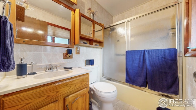 bathroom featuring tile patterned flooring, vanity, toilet, combined bath / shower with glass door, and backsplash