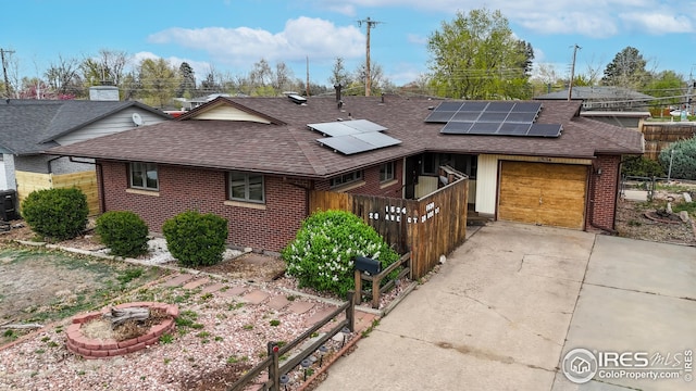 view of front of house with brick siding, a shingled roof, roof mounted solar panels, and concrete driveway