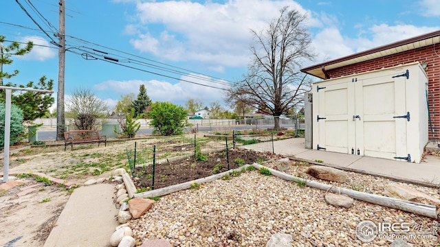 view of yard featuring fence, a storage unit, an outdoor structure, and a vegetable garden