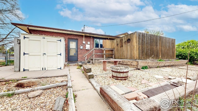 single story home with fence, a storage unit, an outdoor structure, and brick siding