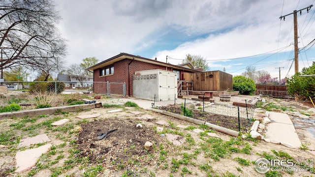 view of home's exterior with brick siding, a garden, and a fenced backyard