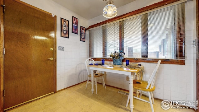 dining space with a healthy amount of sunlight, tile walls, visible vents, and light floors