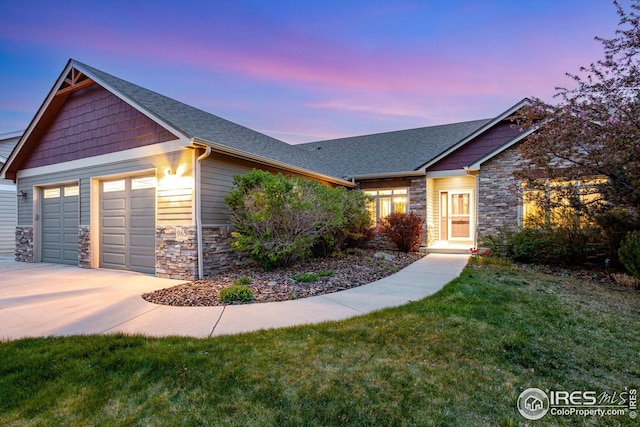 view of front of house featuring roof with shingles, stone siding, a garage, concrete driveway, and a lawn
