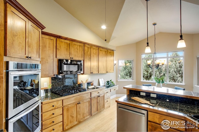 kitchen featuring hanging light fixtures, tile counters, stainless steel appliances, light wood-type flooring, and vaulted ceiling