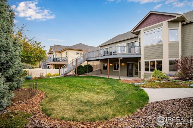 rear view of property with a lawn, a deck, stairway, fence, and a patio
