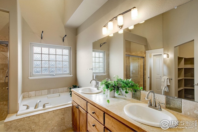 bathroom featuring double vanity, a shower stall, a sink, and a bath