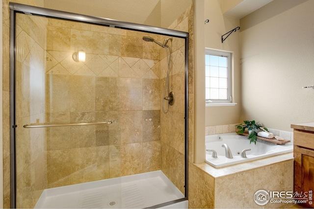 full bathroom with vanity, a bath, and a stall shower