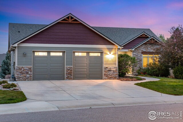 craftsman inspired home with concrete driveway, roof with shingles, an attached garage, and stone siding