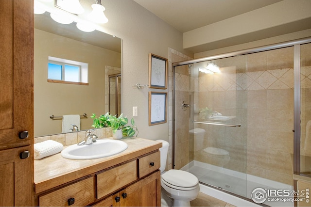 bathroom with vanity, a shower stall, and toilet