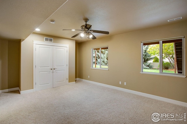 unfurnished bedroom with visible vents, carpet flooring, and multiple windows