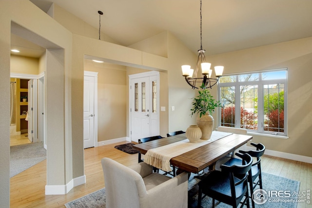 dining room featuring light wood-style floors, baseboards, lofted ceiling, and a chandelier