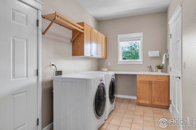 laundry room featuring cabinet space, a sink, light tile patterned floors, baseboards, and separate washer and dryer