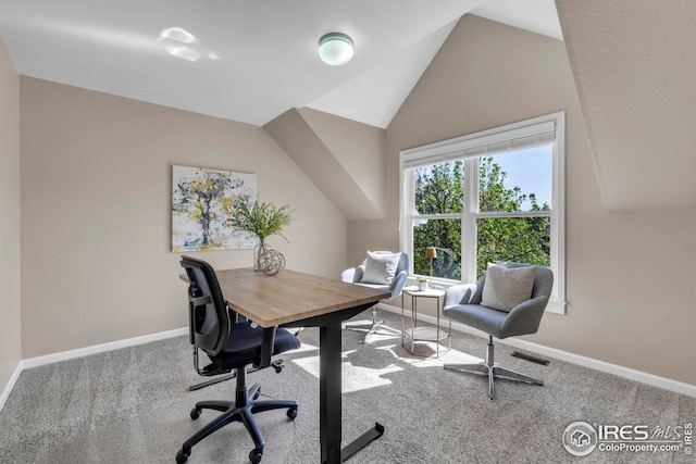 carpeted home office featuring baseboards, lofted ceiling, and visible vents