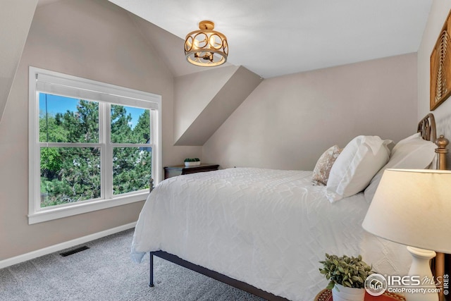 bedroom featuring a notable chandelier, carpet floors, baseboards, lofted ceiling, and visible vents