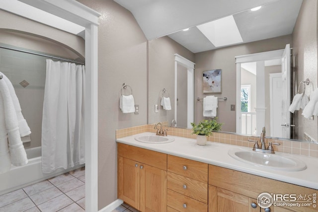 bathroom with a skylight, decorative backsplash, a sink, and tile patterned flooring