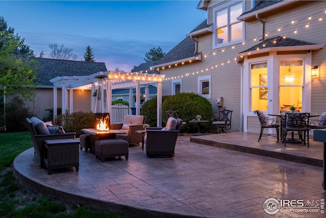 patio terrace at dusk featuring an outdoor fire pit and a pergola