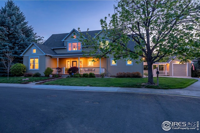 view of front of home with covered porch, concrete driveway, a yard, and an attached garage
