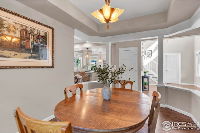 dining area with ornate columns, baseboards, stairs, and wood finished floors