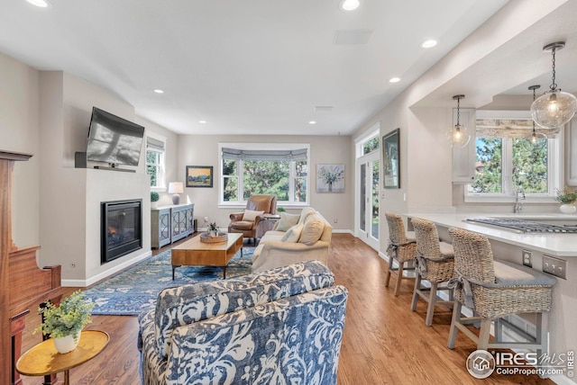 living room featuring plenty of natural light, recessed lighting, baseboards, and light wood-type flooring