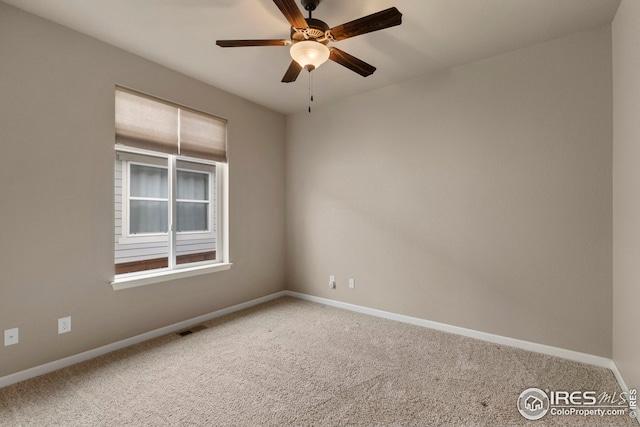 carpeted spare room featuring visible vents, a ceiling fan, and baseboards