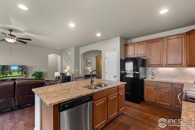 kitchen with a sink, dishwasher, arched walkways, freestanding refrigerator, and open floor plan