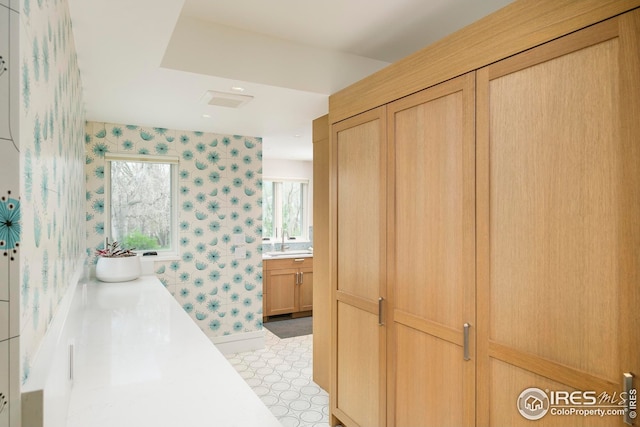 bathroom with vanity, a garden tub, baseboards, wallpapered walls, and tile patterned floors