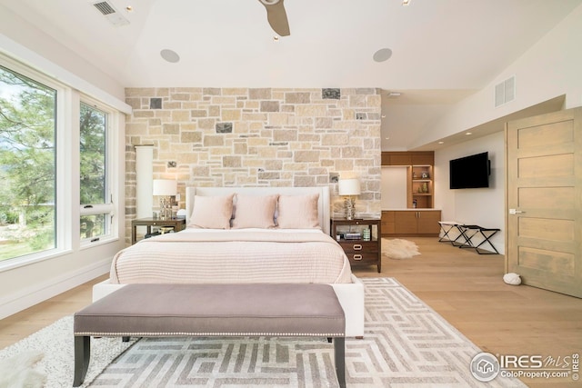 bedroom with vaulted ceiling, wood finished floors, and visible vents