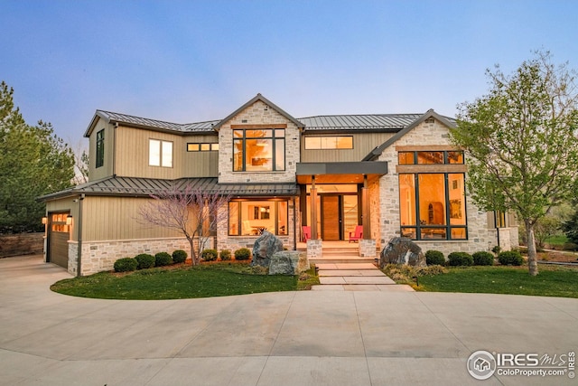 view of front of home with a porch, metal roof, stone siding, and a standing seam roof