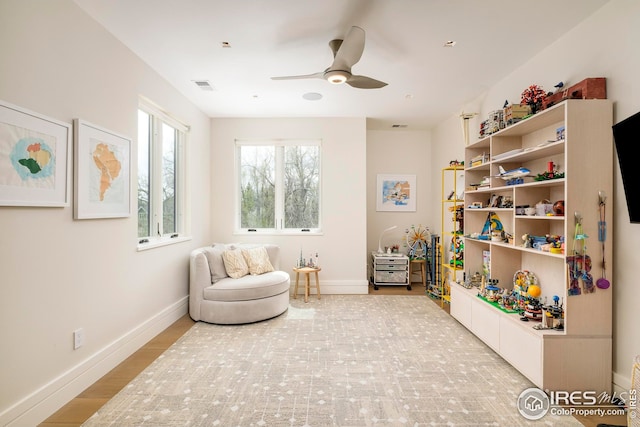 living area featuring visible vents, baseboards, and ceiling fan