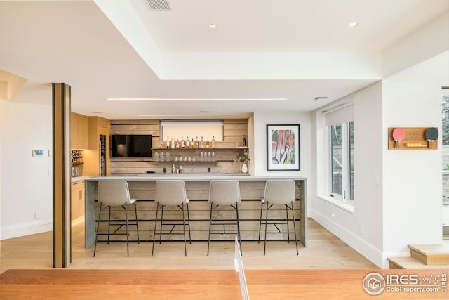 bar with light wood-style floors, bar area, and baseboards