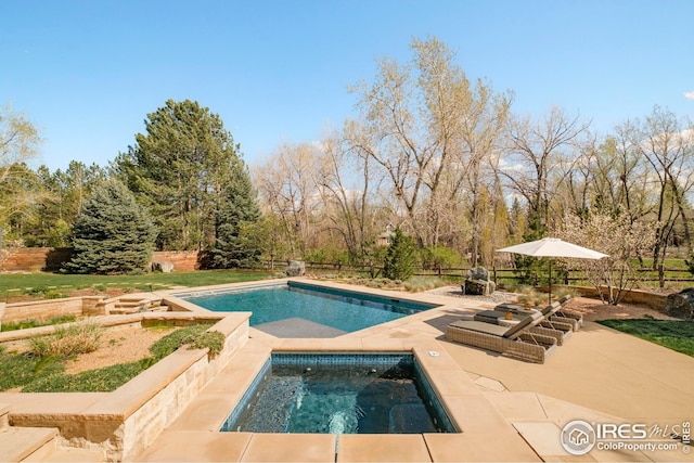pool with fence, an in ground hot tub, and a patio area