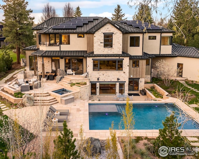back of property featuring an outdoor living space with a fire pit, a balcony, a patio, a standing seam roof, and metal roof