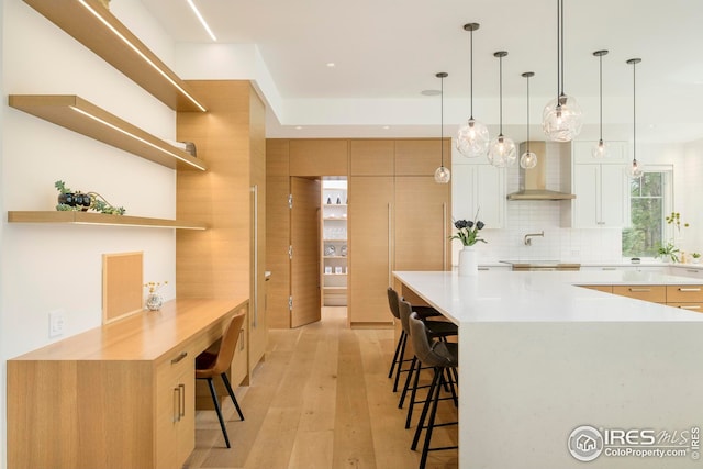 kitchen featuring decorative backsplash, a kitchen breakfast bar, open shelves, light countertops, and light wood-style flooring