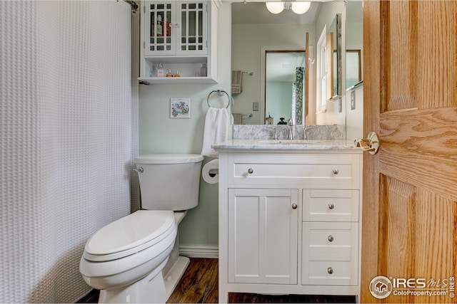 bathroom with curtained shower, wood finished floors, vanity, baseboards, and toilet