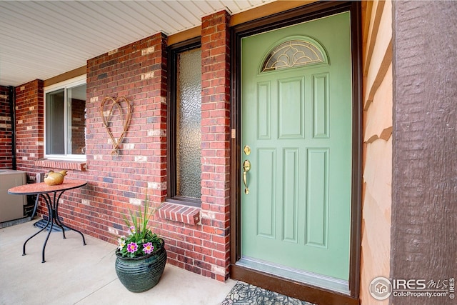 property entrance with brick siding and covered porch