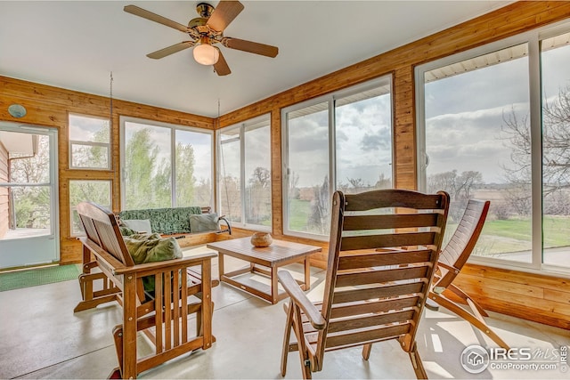 sunroom / solarium with finished concrete floors, wooden walls, and a healthy amount of sunlight