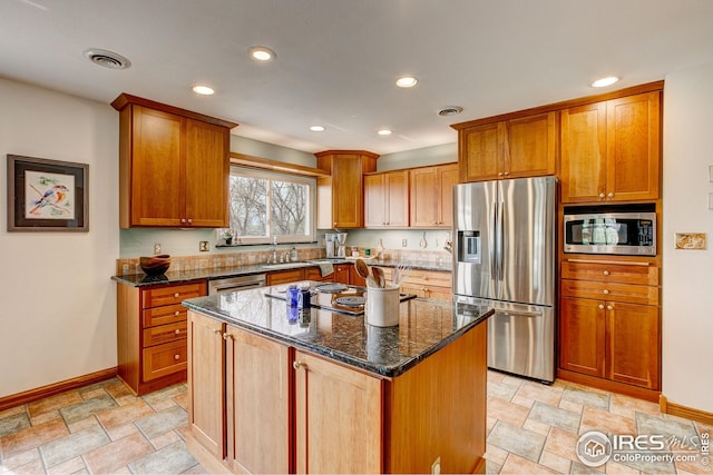 kitchen featuring a center island, dark stone countertops, stainless steel appliances, baseboards, and visible vents