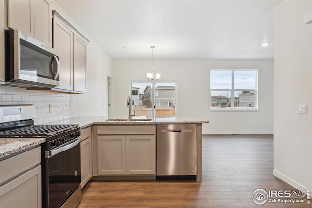 6500 13th St, Frederick, CO 80530 - kitchen featuring a sink, stainless steel appliances, a peninsula, wood finished floors, and tasteful backsplash