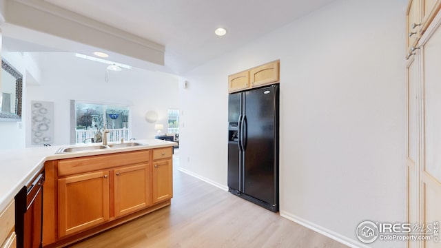 kitchen featuring light wood-style floors, recessed lighting, light countertops, a sink, and black fridge