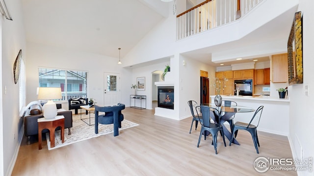 dining room with baseboards, light wood-style flooring, and a towering ceiling