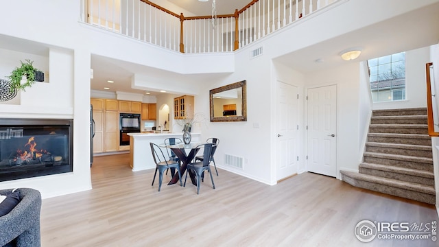dining space featuring visible vents, light wood-style flooring, and stairway