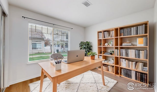 office with a healthy amount of sunlight, baseboards, wood finished floors, and visible vents