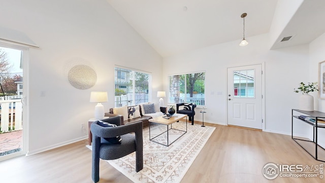 living area featuring high vaulted ceiling, baseboards, and light wood-type flooring