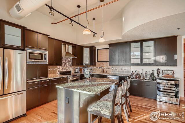 210 W Magnolia St Unit 320, Fort Collins, CO 80521 - kitchen with light wood-style flooring, a sink, stainless steel appliances, wall chimney range hood, and wine cooler