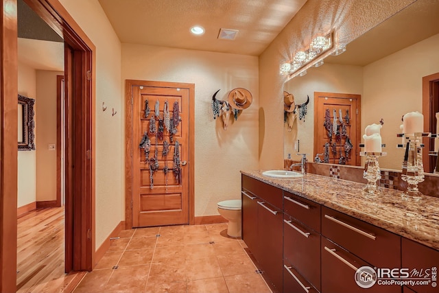 210 W Magnolia St Unit 320, Fort Collins, CO 80521 - bathroom with toilet, vanity, visible vents, a textured wall, and baseboards